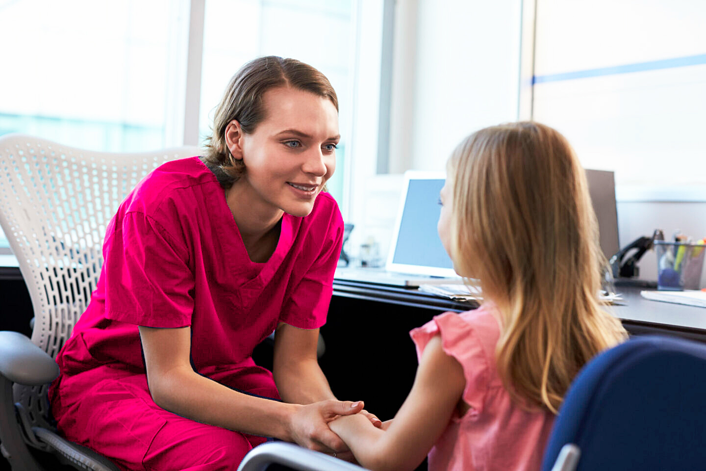 Registered pediatric nurse and young patient sharing stories in home.