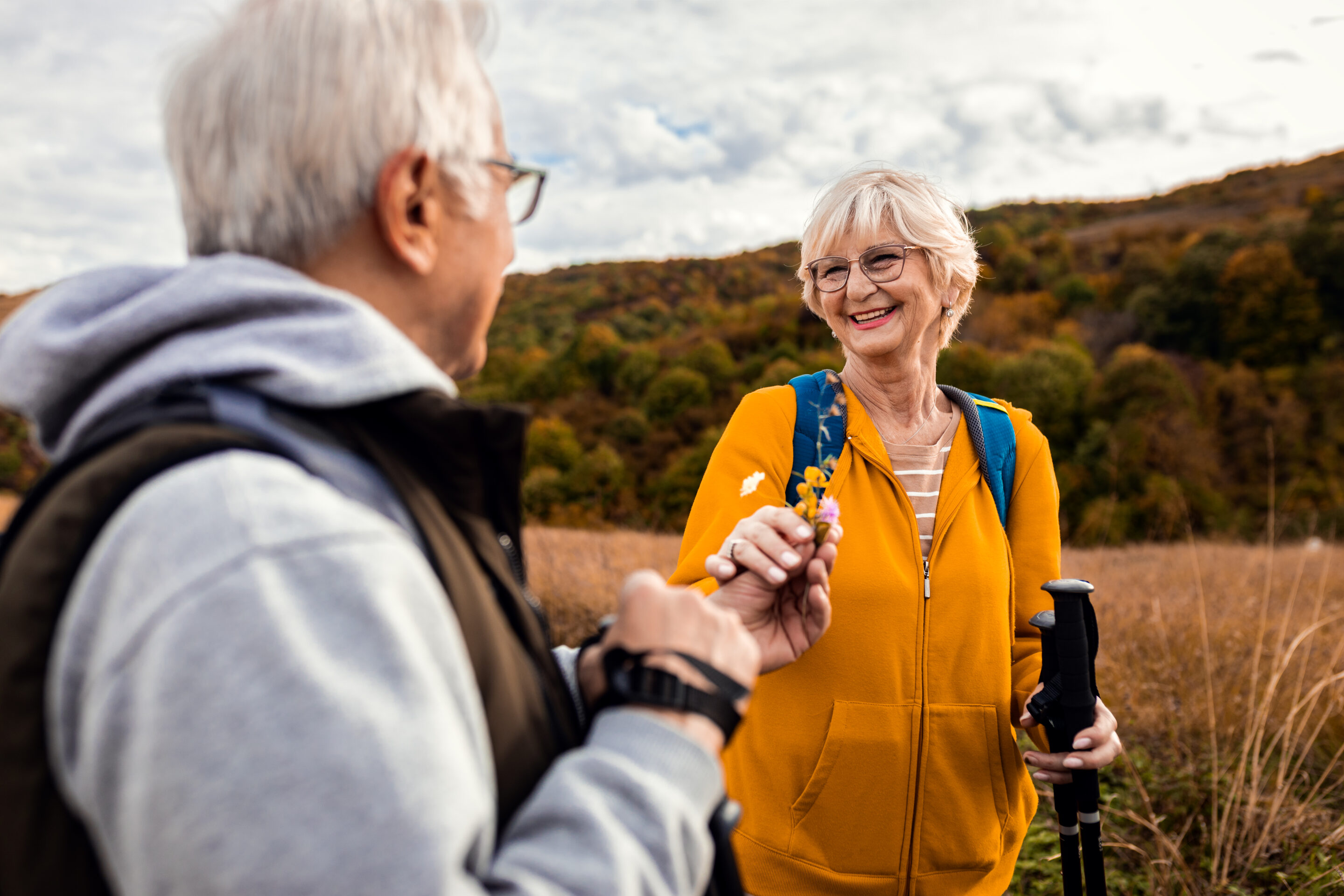 Active senior couple with backpacks hiking together in nature on