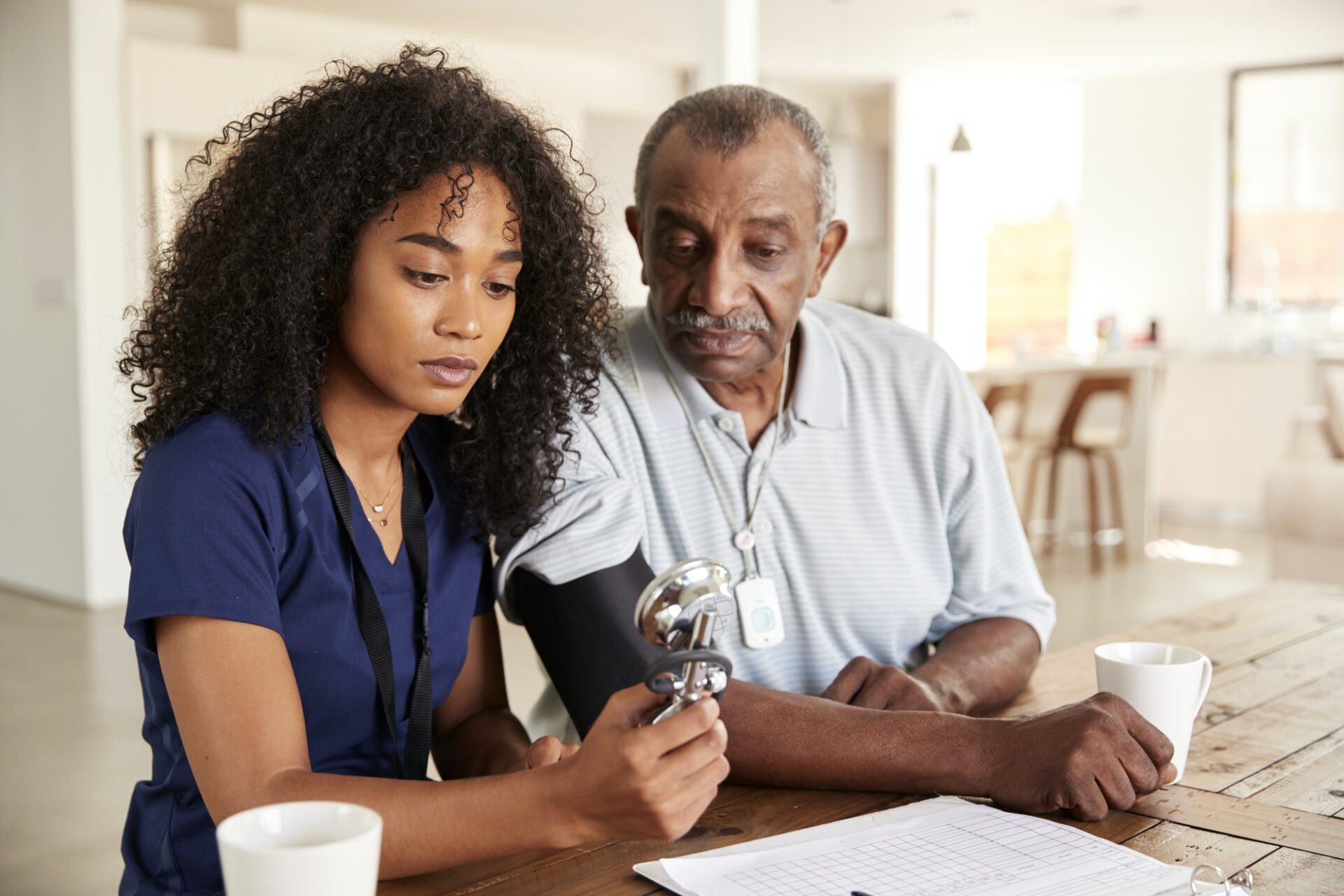 Female healthcare worker checking the blood pressure of a senior man during a home visit