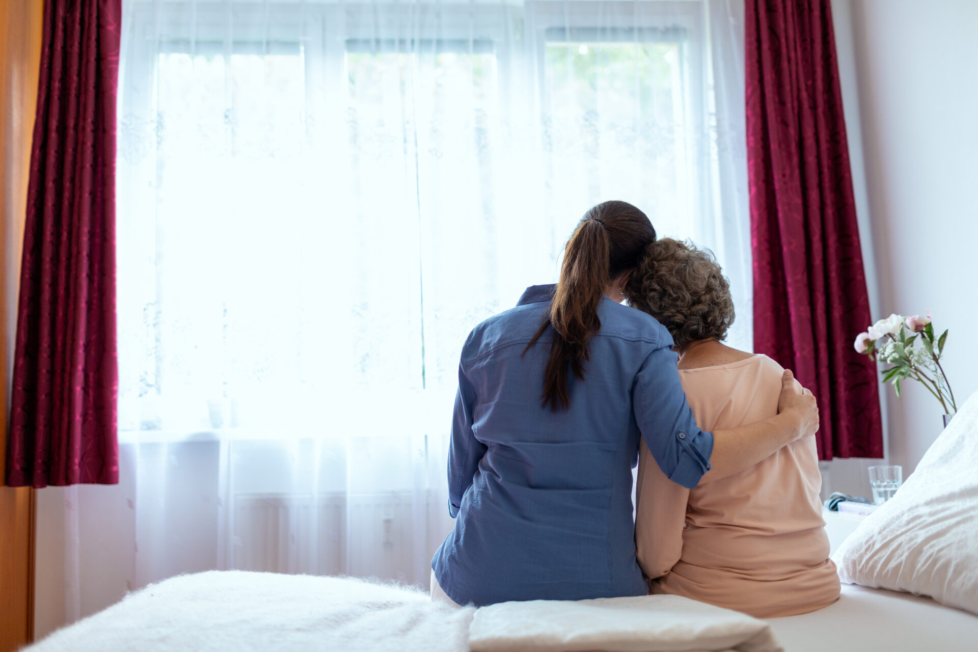 female in home nurse comforts female senior in home