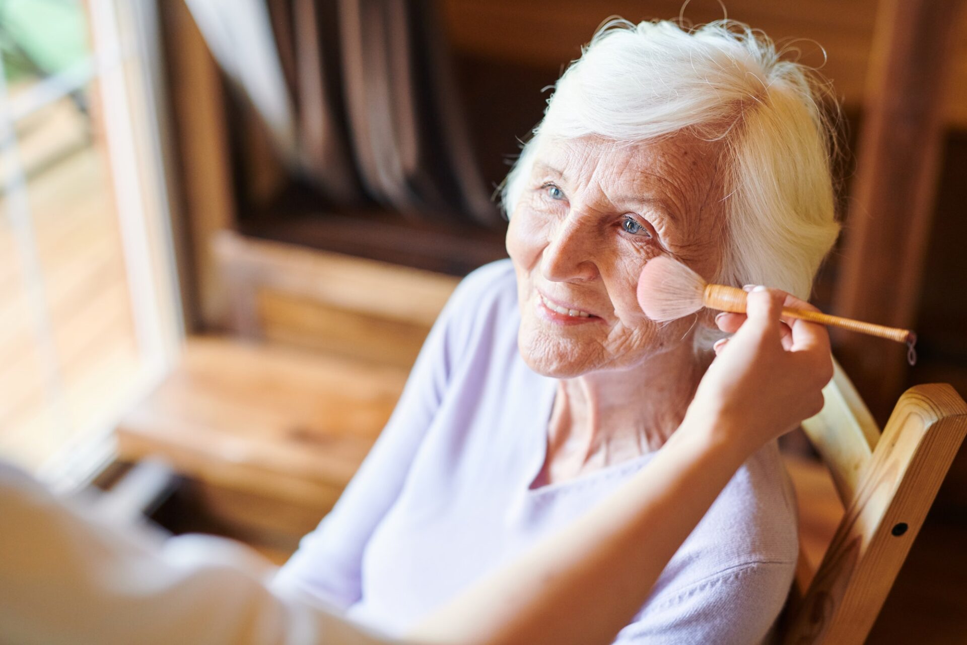 Happy senior female with short white hair looking at beautician