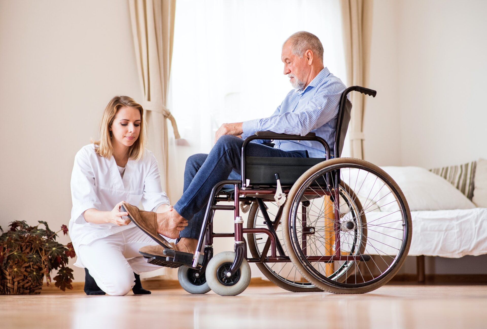 Nurse and senior man in wheelchair during home visit.