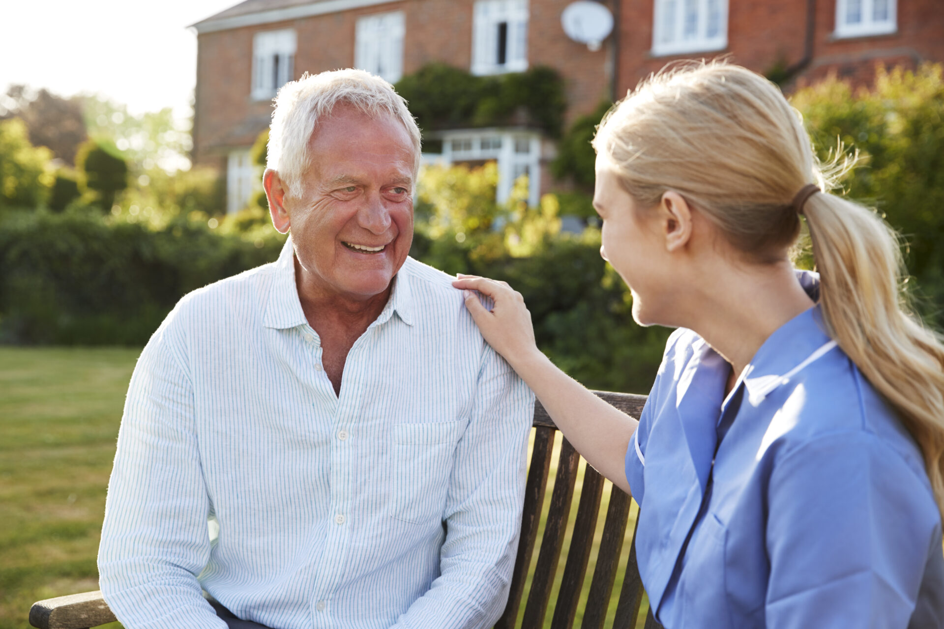 senior caregiver speaking with a man outside a living community.