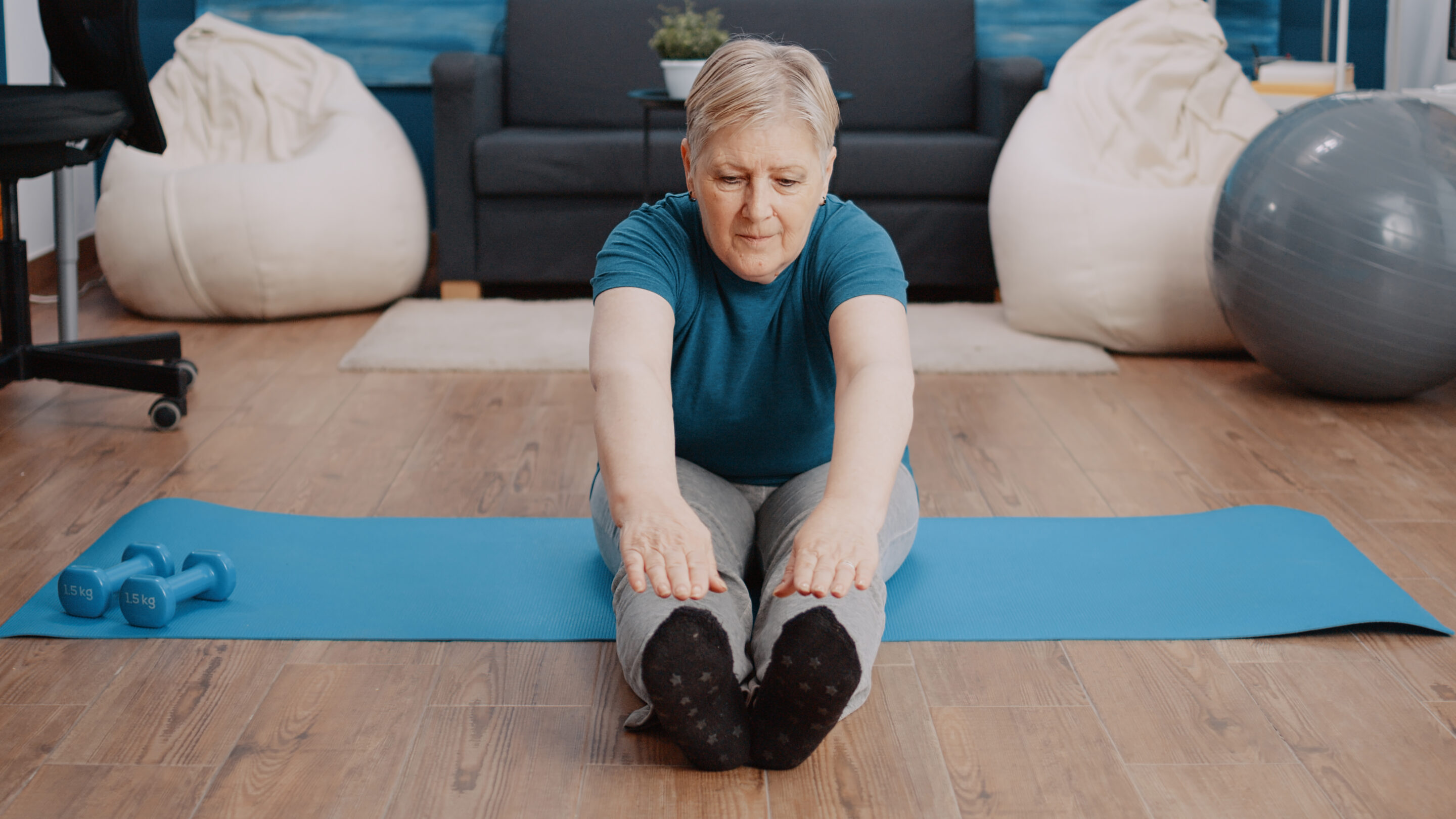 Senior woman stretching in aerobics position on yoga mat